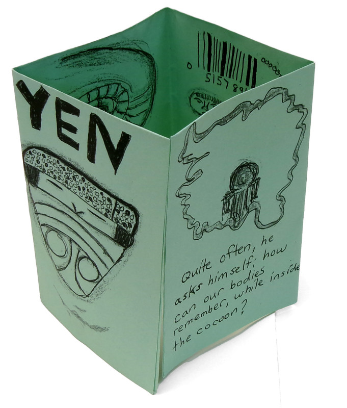The previous zine, seen from another angle. This view shows the front as well as back covers. The back cover has an indistinct drawing and indistinct text.